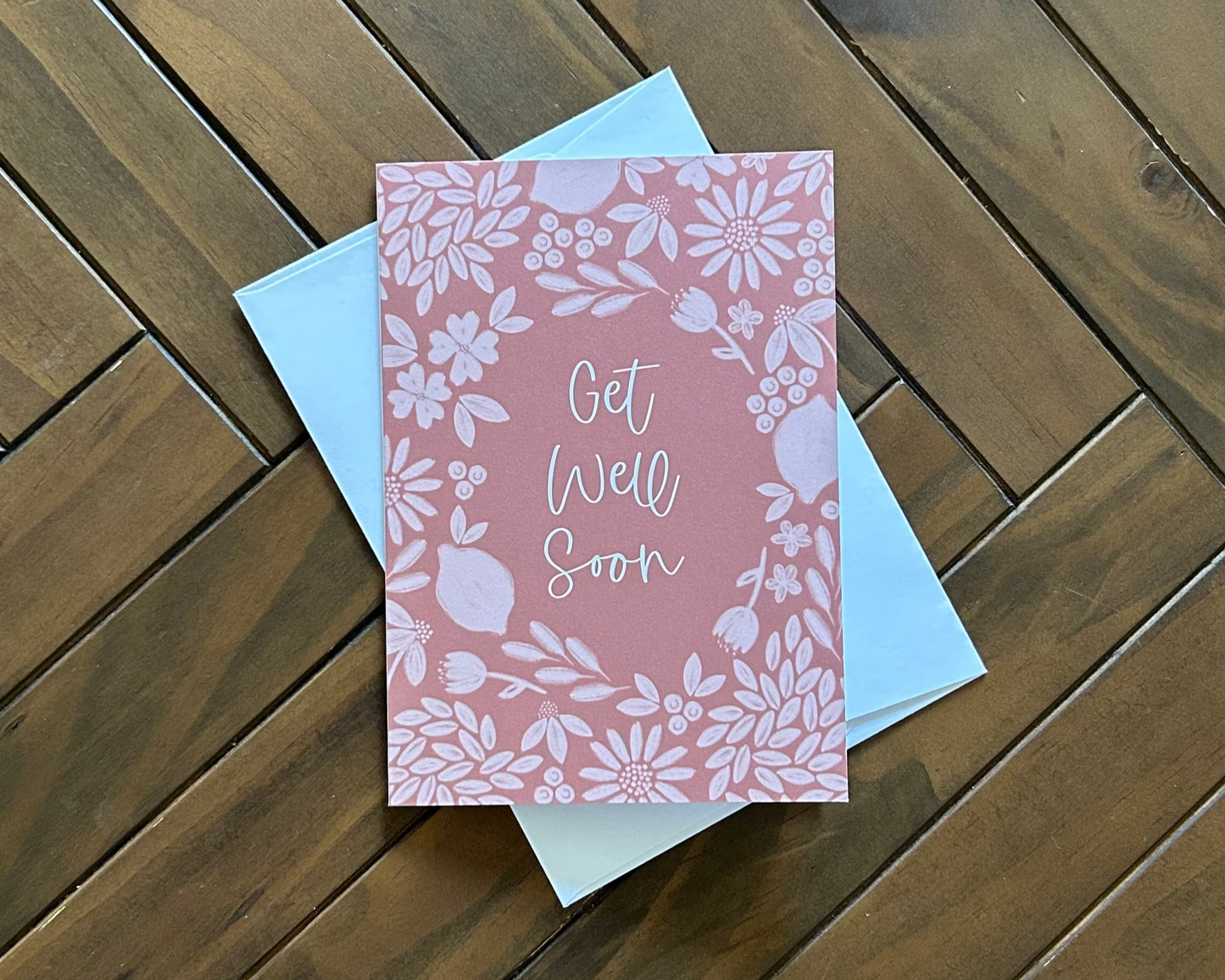 Deep orange floral card with 'Get Well Soon' text on a wooden surface