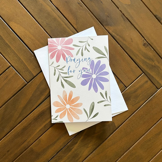Praying for you floral greeting card on a wooden surface