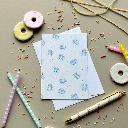 A styled flat-lay of stationery items on a warm beige background, including patterned cards, a pen, straws, and donut-shaped accessories.