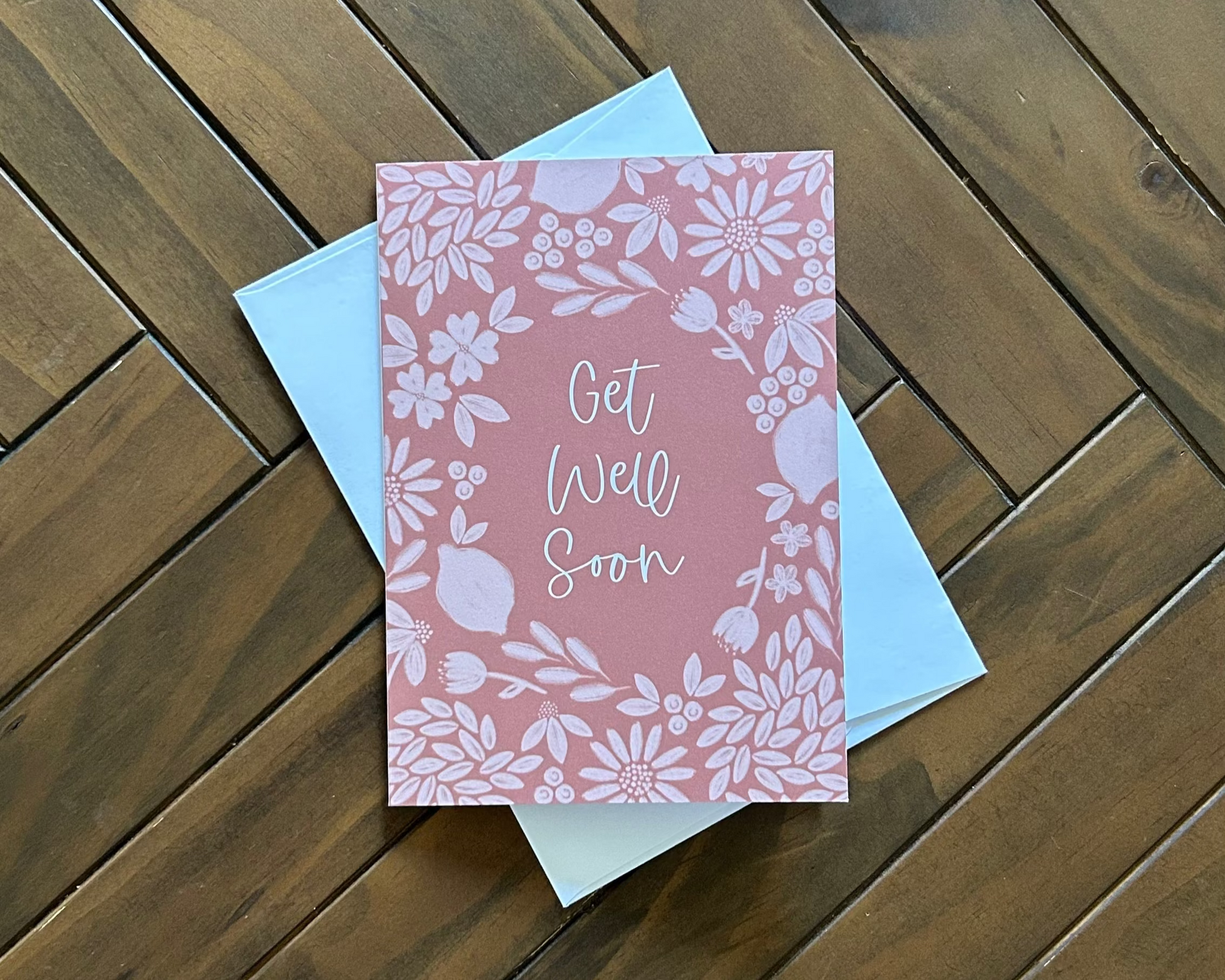 Deep orange floral card with 'Get Well Soon' text on a wooden surface