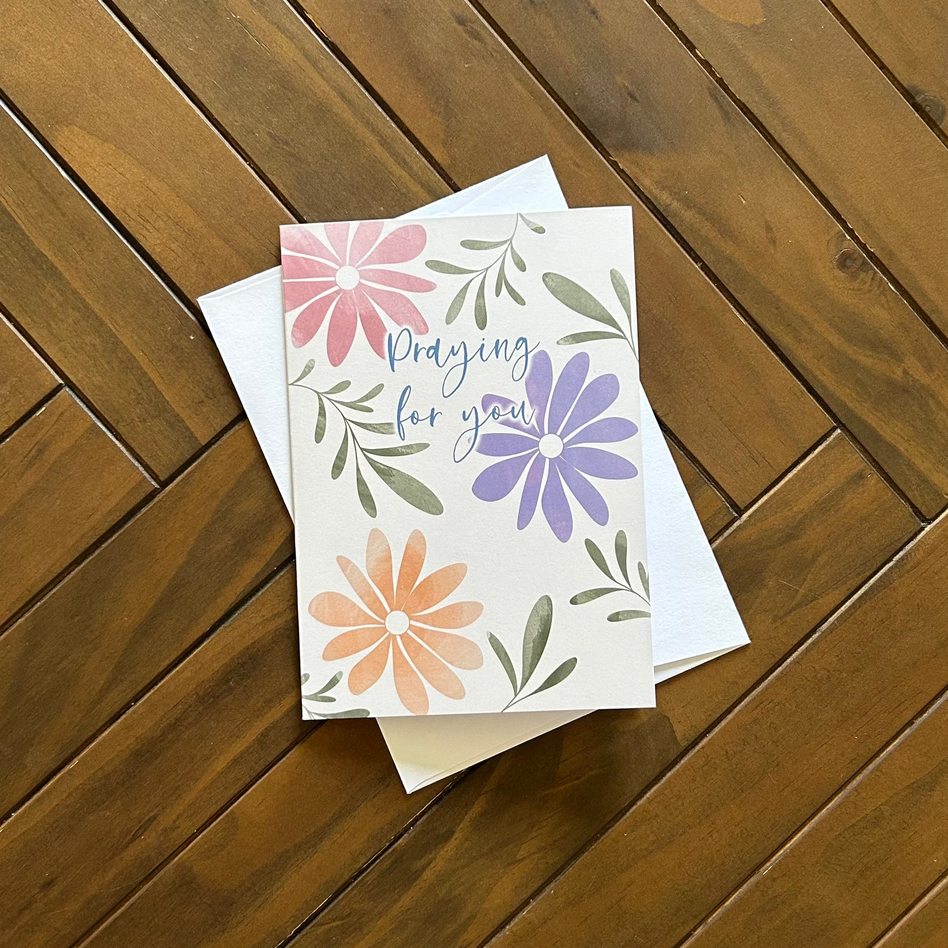 Praying for you floral greeting card on a wooden surface