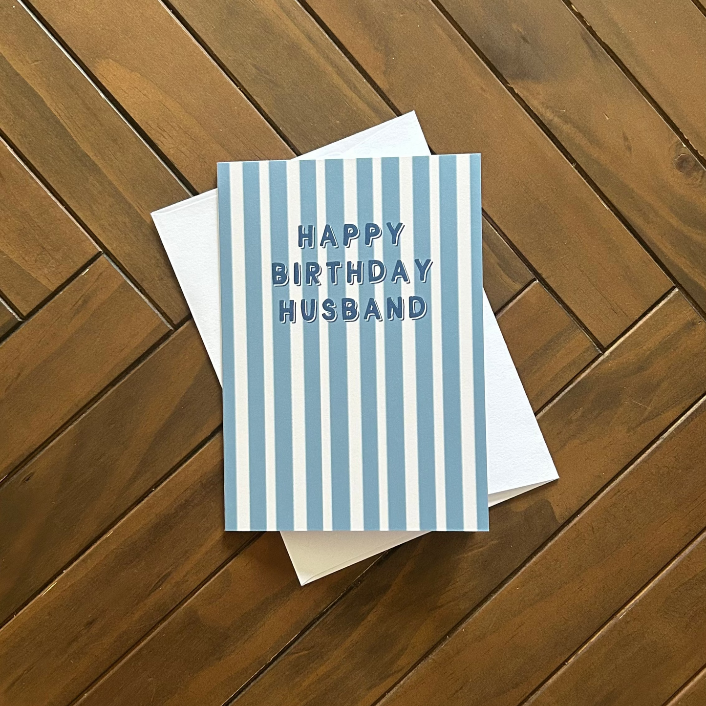 Greeting card with 'Happy Birthday Husband' text on a wooden surface