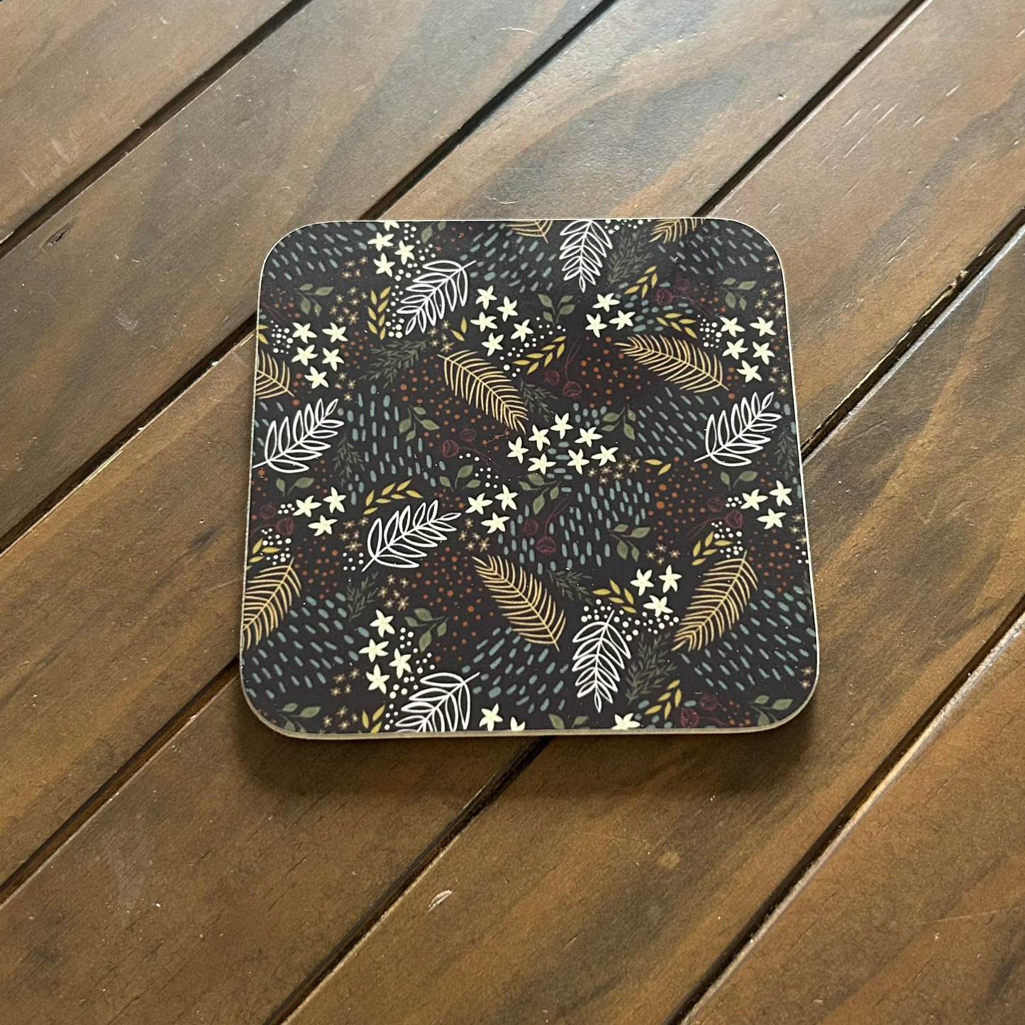Square coaster with autumnal pattern on a wooden surface