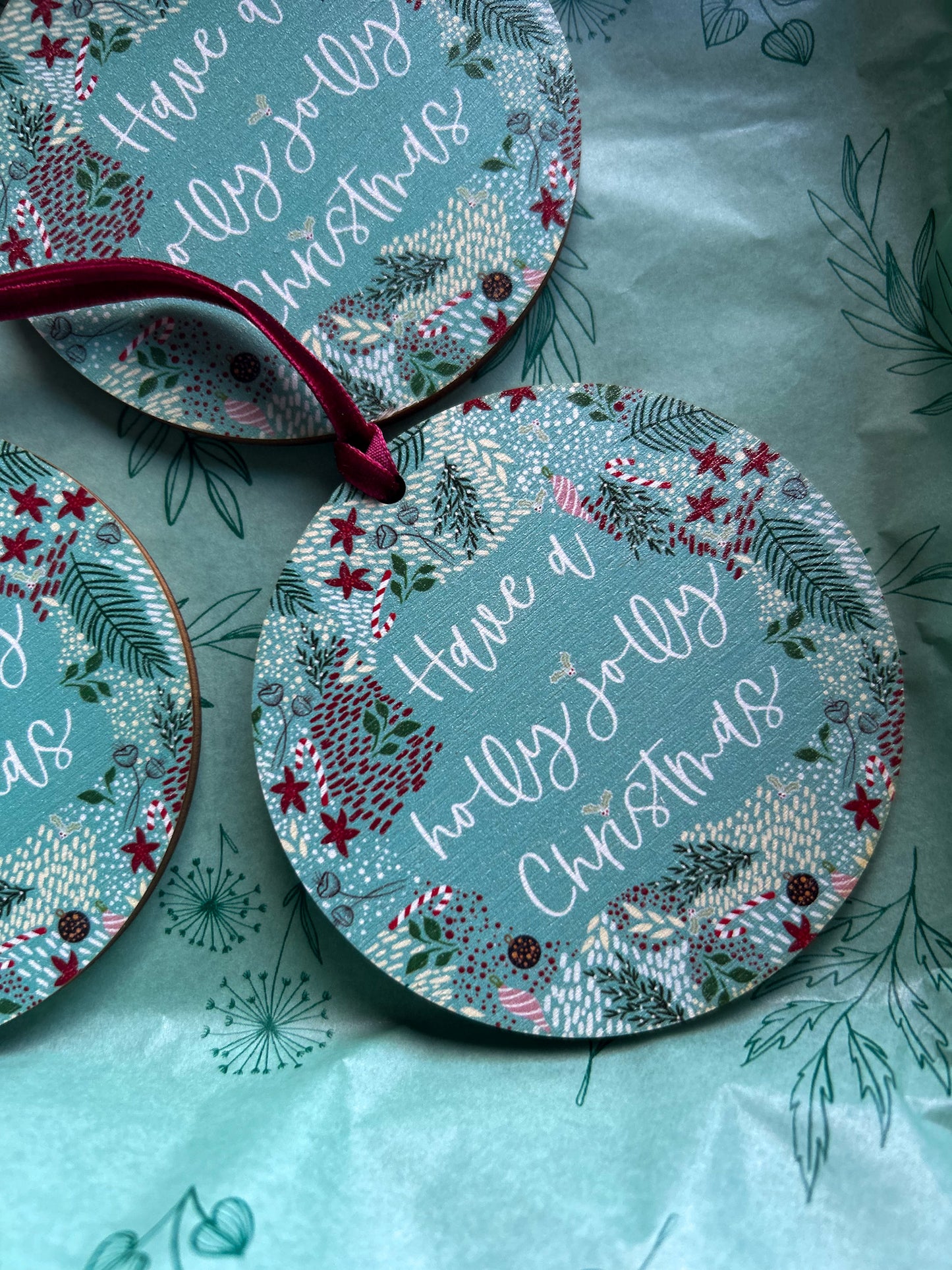 Wooden hanging decorations with 'Have a holly jolly Christmas' on it and a deep red velvet ribbon 